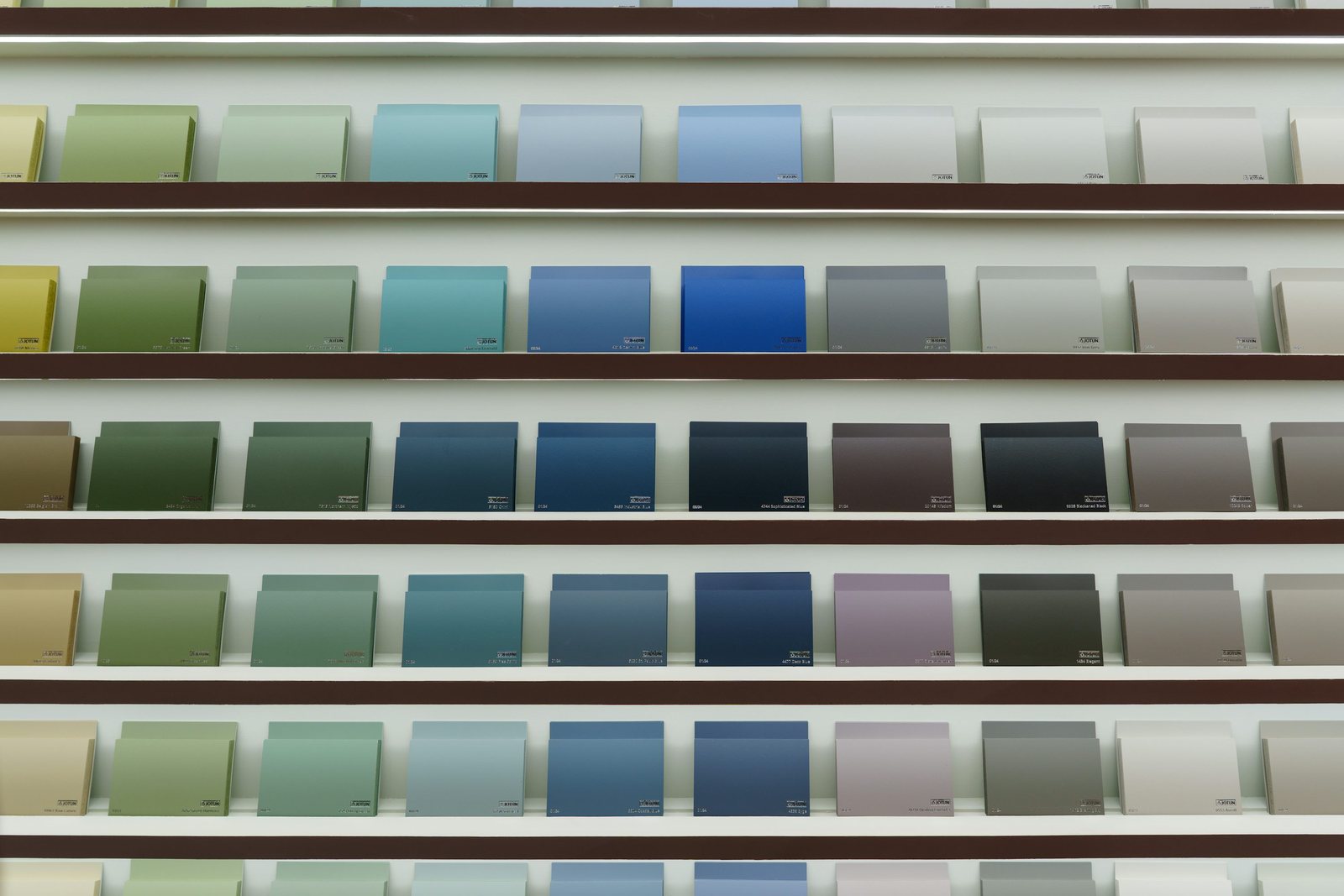 Rows of blue, green and neutral color sample cards displayed on narrow shelves.